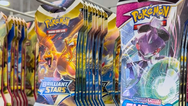 Rows of Pokémon Trading Card Game booster packs hanging on a store display, showing colorful packaging from the Sword & Shield series, including Brilliant Stars packs with illustrated Pokémon characters on the fronts.