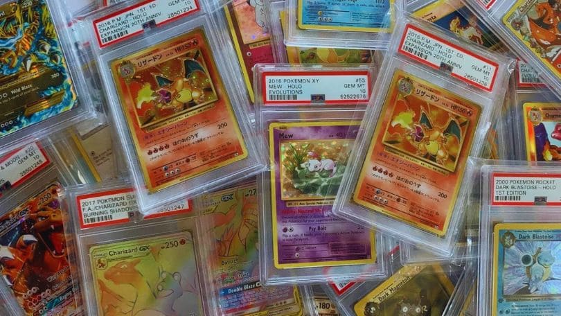 A large pile of PSA Pokémon cards displayed in plastic cases, showcasing various characters and designs.